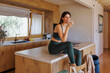 © Westend61 - Woman in activewear sitting on kitchen counter drinking green juice