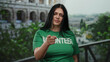 © Krakenimages.com - Woman in green volunteer shirt standing outside roman colosseum in rome, showcasing empowerment and community spirit with a confident expression and open posture.