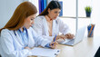 © aFotostock - Two asian women doctors discuss meeting doctor's office medical clinic using laptop consulting patient disease. Asian medical lab young women talking together discussing healthcare assistance teamwork