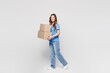 © ViDi Studio - Full body young happy Caucasian woman wears blue t-shirt casual clothes hold blank cardboard box look camera walk go isolated on plain solid white color background studio portrait. Lifestyle concept.