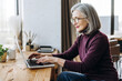 © Maria Vitkovska - Senior freelancer working remotely from home office using laptop