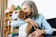 © Maria Vitkovska - Happy, smiling senior woman embracing beagle at home: showing affection and love