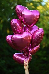 Poster - A bunch of pink heart-shaped balloons tied together with strings.