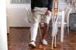 © pabscal - Man leaning on table with broken leg and crutches at home