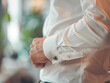 © Kowit - A man in a white dress shirt adjusts his cufflink, preparing for a formal or business occasion.