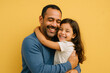 © Midea  - Father embraces daughter in front of yellow wall.