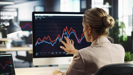 Poster - Focused Businesswoman Analyzing Stock Market Charts on Computer Monitor in Modern Office with beige Suit And Financial Data Graphs
