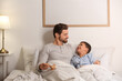 © Pixel-Shot - Father with toy plane and his little son lying in bedroom
