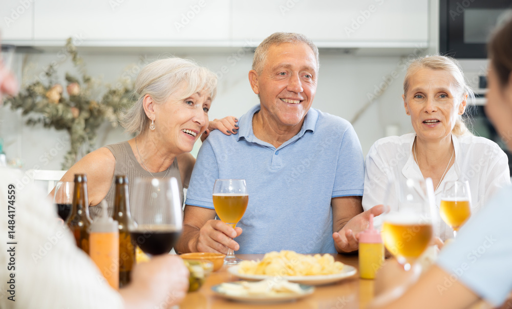 Group of joyful elderly women and man gathered around cozy kitchen ...