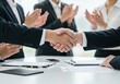 © Vooglo - Business people shaking hands after a successful meeting with colleagues applauding in the background