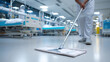 © tong2530 - Cleaning staff disinfecting hospital floor with mop, sterile interior with medical beds and sanitation equipment in the background