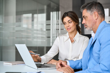 Fototapete - Mature business woman professional bank manager or financial advisor consulting client using laptop. Two older executives team business people man and woman working at office corporate meeting.