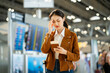 © Chanakon - Stressed young asian businesswoman traveler confused missing flight and using smartphone to check flight information and holding passport and boarding pass standing in the airport terminal.