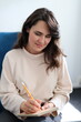 © Andrii Zastrozhnov - Young caucasian female writing with pencil in notebook at home