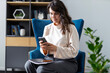 © Andrii Zastrozhnov - Caucasian young adult female using smartphone at home in modern living room