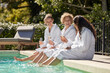 © Rido - Women friends relax at poolside while drinking champagne