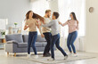 © Studio Romantic - Happy family with children sharing moments of joy and laughter while having fun at home. Children and their parents energetically dance, run, and spin on a rug in a cozy living room. Family concept.
