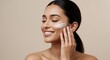 © Grosir - Smiling Woman Applying Cream to Face in Studio Setting for Skincare Advertisement and Cream Isolated