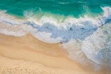 Vista aérea de las olas del océano golpeando la playa de arena, mostrando su fuerza y ​​belleza. El agua turquesa con espuma blanca