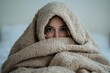 © Color Orbit - A woman wrapped in a beige knitted blanket with her eyes visible against a blurred background indoors