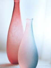 Poster - Elegant and Soft Hued Glass Vases in Pink and Blue Colors on a Bright Background Ideal for Home Decor and Aesthetic Designs