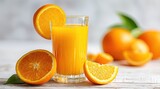 Freshly squeezed orange juice in a glass, garnished with orange slices, surrounded by whole and sliced oranges
