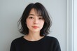 © AnilaStudio - Portrait of a young Asian woman with short wavy hair against a plain background