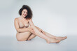© deagreez - Young woman embracing her natural beauty and body positivity in a serene studio setting