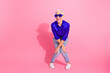 © deagreez - Energized senior woman in blue shirt posing confidently with a bold attitude against a bright pink background