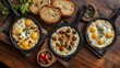 © Hutan - Three cast iron skillets of fried eggs, alongside bread and herbs, on a wooden table