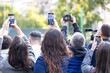 © wellphoto - Crowd of people raising smartphones and cameras to capture outdoor media event. Mobile or citizen journalism concept.