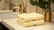 © ADI - Soft yellow hand towels on marble countertop in modern bathroom
