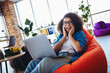 © deagreez - Cheerful young businesswoman excited while working on a laptop in a stylish office lounge area with modern decor