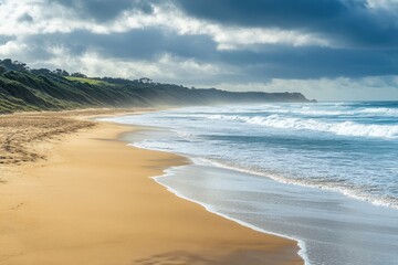 Wall Mural - Guvvos beach showcases long sand strip and sea waves under cloudy sky, Guvvos beach long sand strip and sea waves on Great Ocean Road route Australia