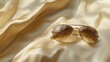 © ADI - Gold aviator sunglasses on beige silk fabric fashion accessory summer style