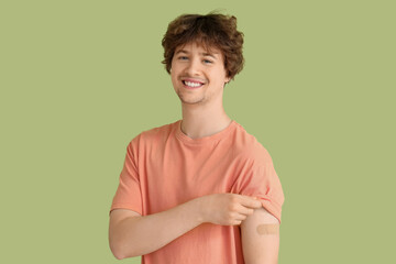 Young man with applied medical patch on green background. Vaccination concept