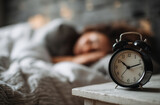 cozy bedroom scene featuring vintage alarm clock bedside table, with person peacefully sleeping background. soft lighting