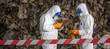 © BESTIMAGE - Two scientists in protective suits conducting environmental analysis at waste disposal site with hazardous materials and contaminated rocks in an outdoor setting
