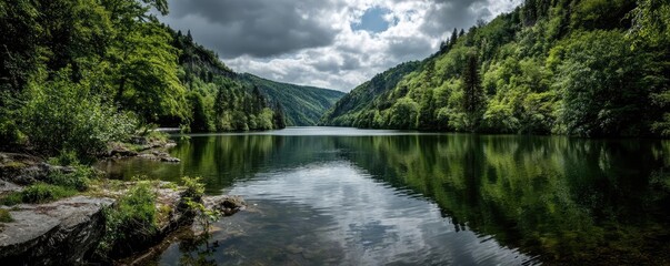 Poster - Scenic view of lake in pine forest under cloudy blue sky concept. Serene lake reflecting hills under a dramatic sky in nature.