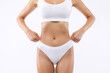 © Home-stock - Unrecognizable fit young woman with slim body in white underwear pulling up panties, standing isolated on white studio background