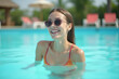 © LIUBOMYR - woman posing by the pool Laughing Woman in a swimming pool looking at the camera at a resort stylish sunglasses near sparkling  Fictional Character.generative ai