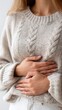 © Shivani - A close-up of a Korean woman, gently holding her belly with both hands. The background