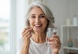 © Ozz - A happy senior woman taking a vitamin pill with a glass of water, smiling brightly.