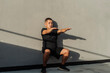© Mdv Edwards - Middle-aged Southeast Asian man holds a wall sit with arms raised, showing control, endurance and core activation during bodyweight isometric training.
