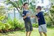 © Austockphoto - Two brothers tackling on the grass outside