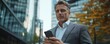 © valentine - Businessman using smartphone in urban setting