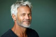 © R - Green solid background. A modern man in his 40s with a stylish appearance. Trendy men's crew cut haircut - midlife white man with white hair. Visual idea of style for aging men.