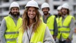 © Evgenii - Group of construction workers with safety helmets and vests stand at a building site, smiling and enjoying camaraderie during the day. Bright yellow vests enhance their visibility