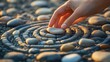 © shobakhul - A hand placing a stone in a patterned stone circle design.