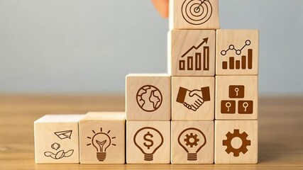 Poster - Hand placing target block on wooden blocks with business icons on a wooden surface against gray wall